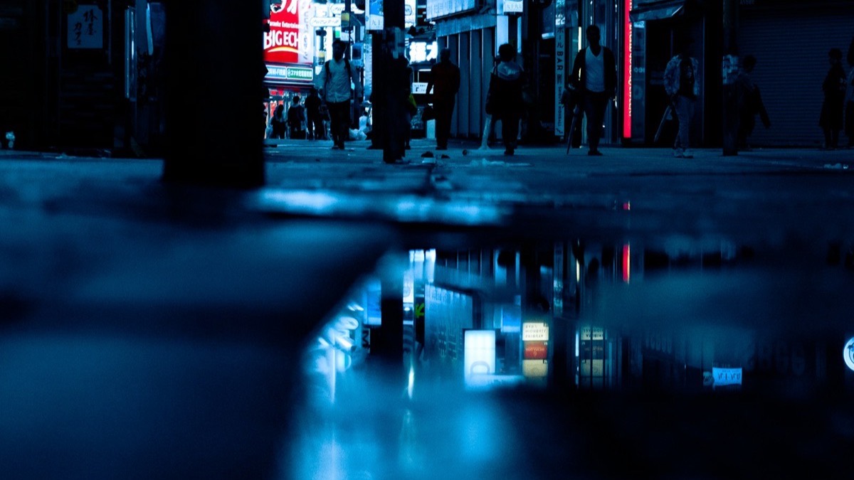 A Tokyo shopping street reflected in rain at night